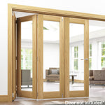 Lifestyle prefinished oak bifold frame kit with glazed folding doors in a bright room