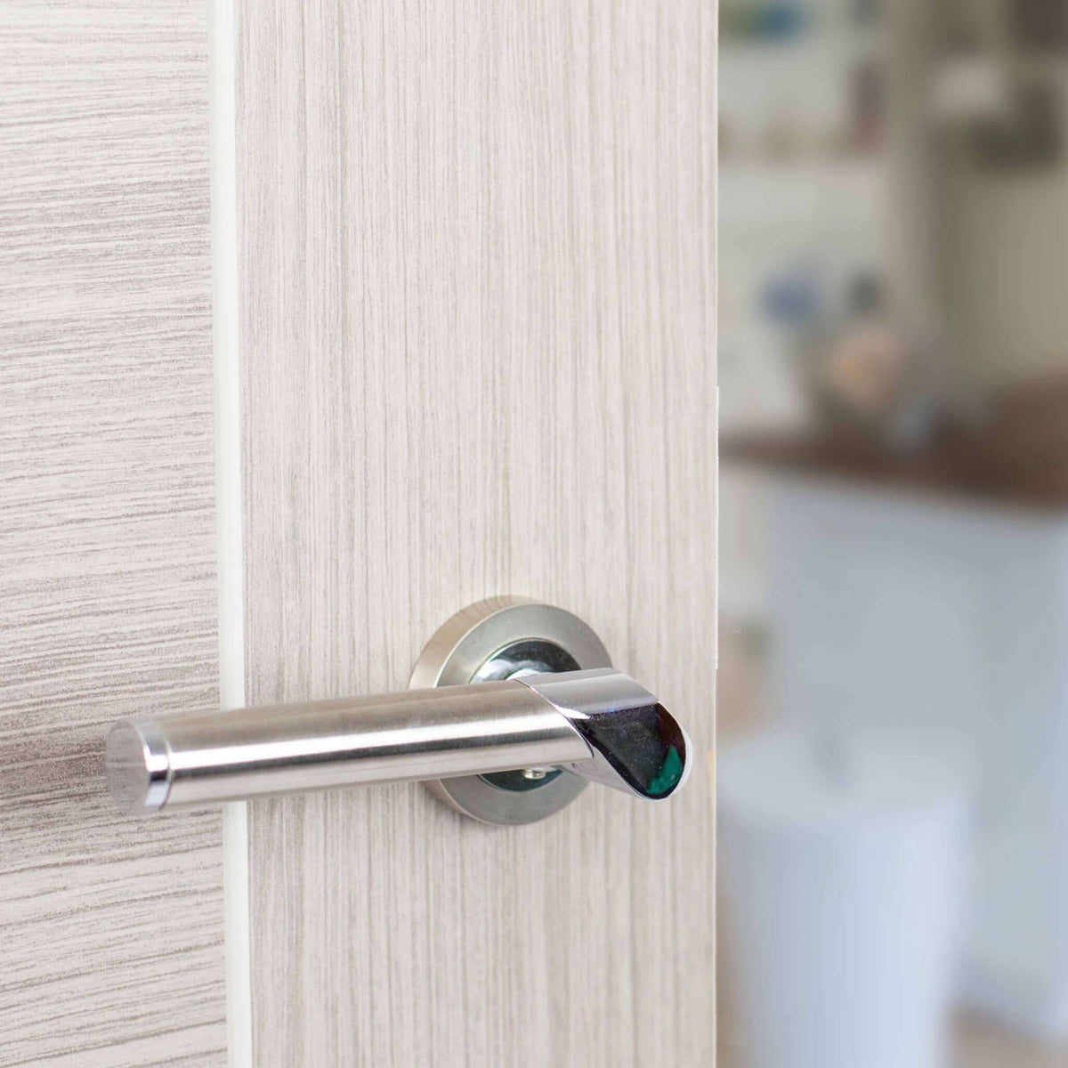 Lifestyle Tunis satin nickel and polished chrome lever handle installed on a white door