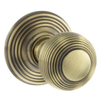 A pair of round antique brass door knobs with concentric ring detailing, shown on a plain white background.