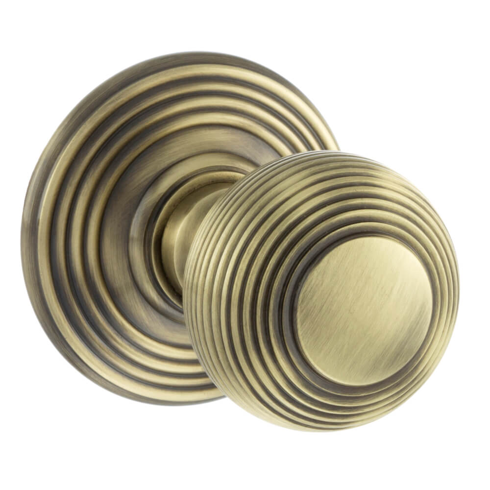 A pair of round antique brass door knobs with concentric ring detailing, shown on a plain white background.