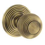 A pair of round matt antique brass door knobs with concentric ring detailing, shown on a plain white background.