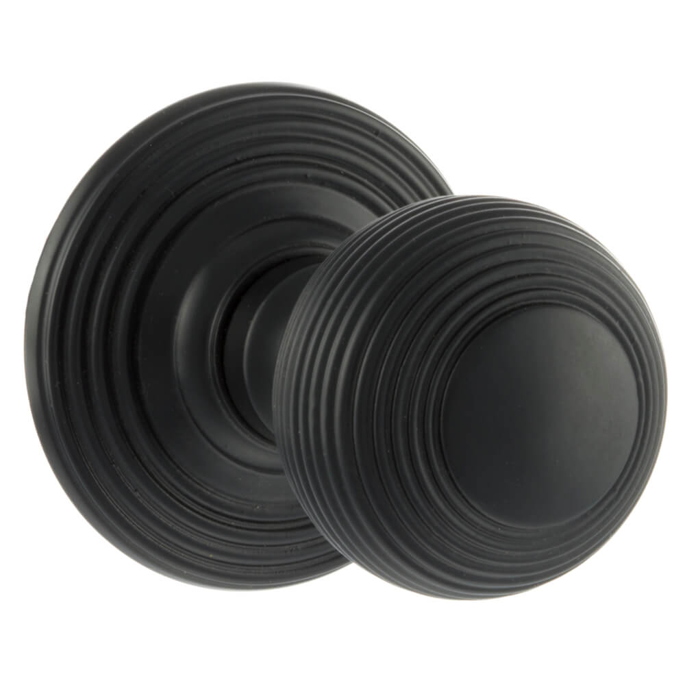 A pair of round matt black door knobs with concentric ring detailing, shown on a plain white background.