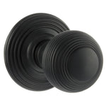 A pair of round matt black door knobs with concentric ring detailing, shown on a plain white background.