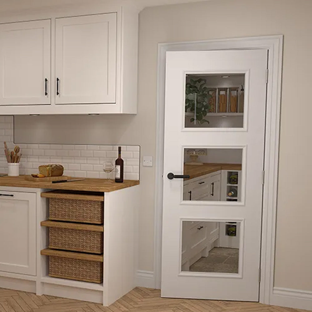 Deanta White Primed 3 Panelled Glazed Door Lifestyle in a Kitchen Setting with black handles in a white frame.